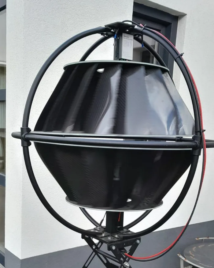 Close-up van de Greenmil-turbine: een rotor van carbonfiber binnen een dragend ringframe, gemonteerd naast een woning.